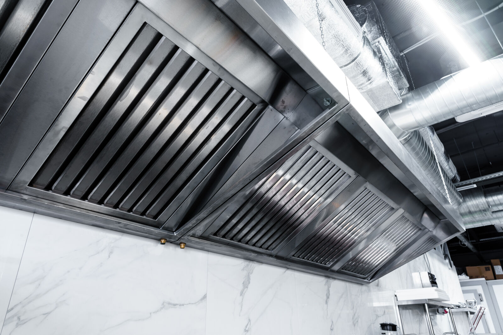 A clean stainless steel extraction hood over a professional kitchen line